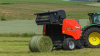 KUHN FB 3130 round baler producing a net bound grass bale in a hilly area.